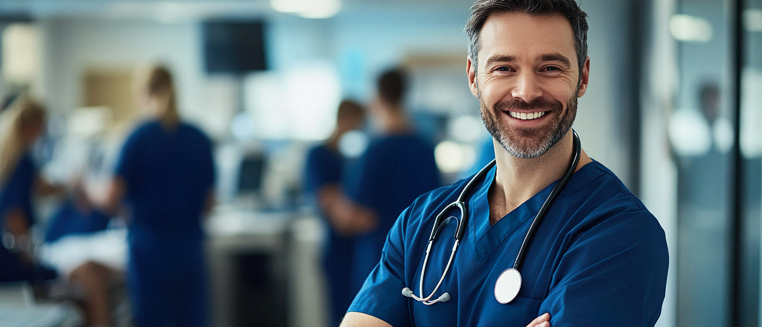 Pewny siebie doktor w niebieskim scrubsie, uśmiechający się ciepło w szpitalnym środowisku